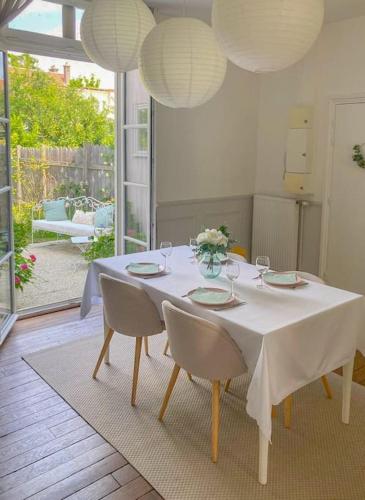 une table à manger avec des chaises et un tissu de table blanc dans l'établissement Le Jardin Des Délices charming house in Troyes, à Troyes