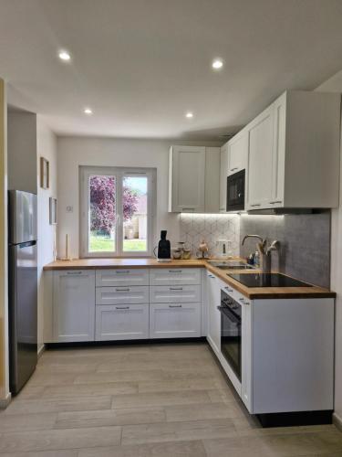 a white kitchen with white cabinets and a window at Chill House - Maison 2 chambres - Option Jacuzzi in Chevannes