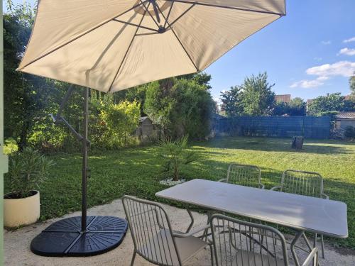 a table and chairs with an umbrella on a patio at Chill House - Maison 2 chambres - Option Jacuzzi in Chevannes