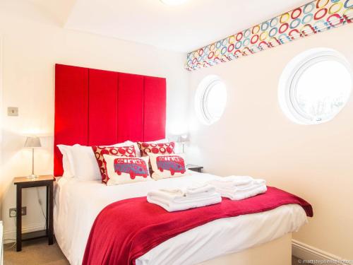 a bedroom with a red headboard and a white bed at Alum Chine Beach House in Bournemouth
