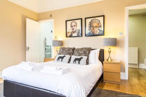 a bedroom with a large white bed with pictures on the wall at Alum Chine Beach House in Bournemouth