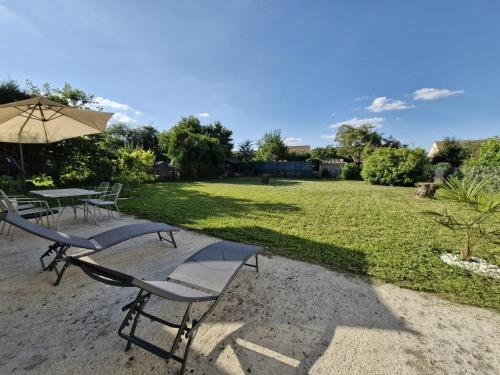 a table and chairs with an umbrella and a lawn at Chill House - Maison 2 chambres - Option Jacuzzi in Chevannes