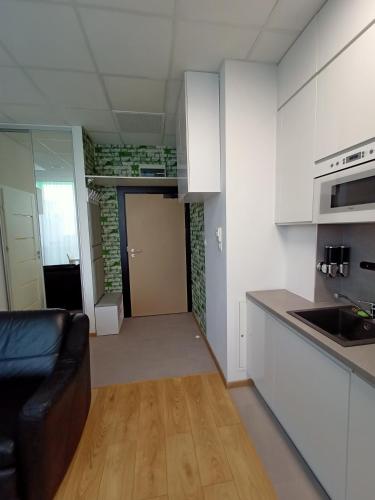a kitchen with white cabinets and a black couch in a room at Zlatarooms in Warsaw
