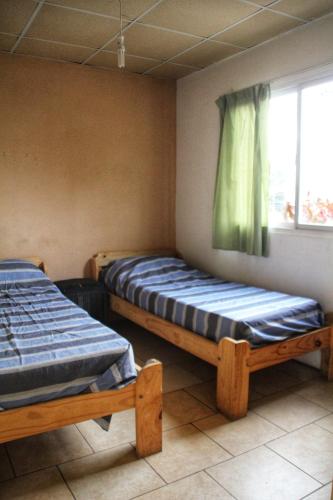 two beds in a room with a window at La Vecindad in Córdoba