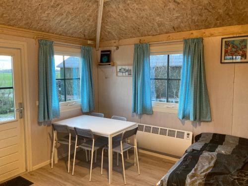Hooiberghut op boerderij في لايدسخيندام: غرفة نوم مع طاولة وكراسي وسرير