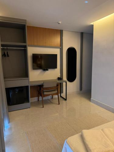 a room with a tv and a table and a bed at Oásis Hotel in Miracema do Norte