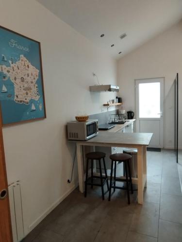 une cuisine avec un comptoir et une table avec des tabourets dans l'établissement Maisonnette proche mer, à Lannion