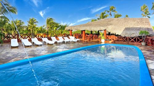 a resort pool with chairs and a thatch roof at Pousada do Norte in Jericoacoara