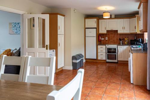 a kitchen with white cabinets and a table and chairs at Kerry Holiday Homes at the Killarney Holiday Village in Killarney