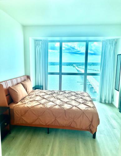 a bedroom with a bed and a large window at Luxe Waterfront Penthouse in Fort Myers