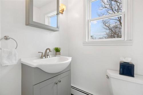 a white bathroom with a sink and a window at Nantasket Nest in Hull