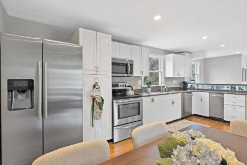 a kitchen with white cabinets and a stainless steel refrigerator at Nantasket Nest in Hull