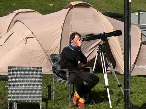 a man sitting in front of a camera in front of a tent at Zeta Camping in Jut'a