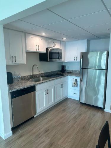 a kitchen with white cabinets and a stainless steel refrigerator at Luxe Waterfront Penthouse in Fort Myers