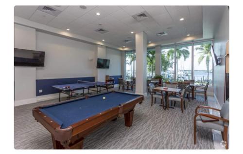 a pool table in a room with tables and chairs at Stunning Water View Suite in Fort Myers