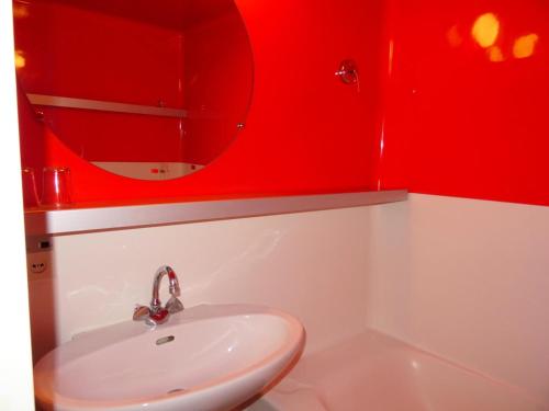La salle de bains rouge est pourvue d'un lavabo et d'un miroir. dans l'établissement Résidence Lauzieres - Studio 5 personnes skis aux pieds et proche des commerces dans le village du Charvet à Arc 1800 MAE-1901, à Arc 1800