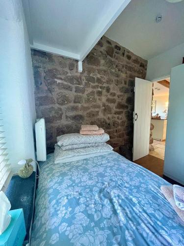 a bedroom with a bed with a stone wall at Top Barn Wales in Monmouth