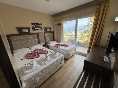 a hotel room with two beds and a large window at Selinus Beach Club Hotel in Gazipasa