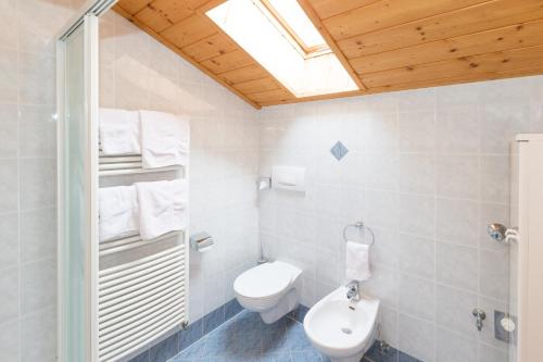 a white bathroom with a toilet and a window at Obergostnerhof in Chiusa