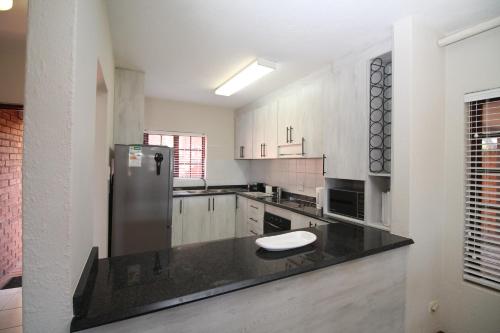 a kitchen with a stainless steel refrigerator and white cabinets at Shelly De La Mer 5 in Shelly Beach