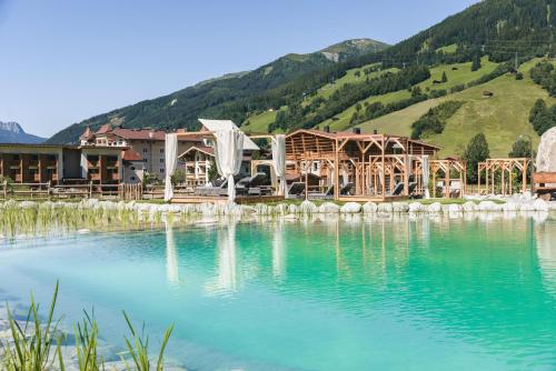 a resort with a lake in front of a mountain at Traumhotel Alpina Superior Adults only Hotel in Gerlos