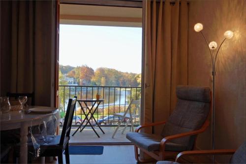 d'un salon avec une table et une vue sur un balcon. dans l'établissement Studio face au lac, à Bagnoles-de-l'Orne