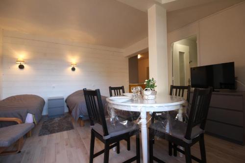 - un salon avec une table à manger, des chaises et une télévision dans l'établissement Studio face au lac, à Bagnoles-de-l'Orne