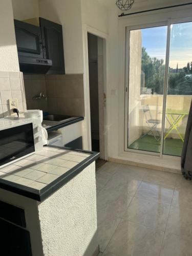 d'une cuisine avec vue sur une porte coulissante en verre. dans l'établissement Montpellier : Jolie studio très calme, à Montpellier