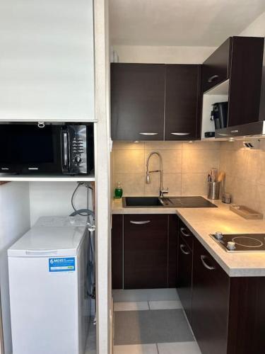 La cuisine est équipée de placards bruns et d'un réfrigérateur blanc. dans l'établissement Studio Strasbourg proche gare, à Strasbourg