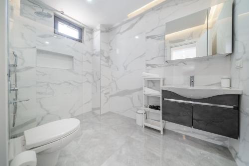 a white bathroom with a toilet and a sink at Villa Bella in Kum