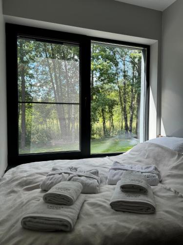 a bed with three towels on it with a window at Lavender Resort in Molėtai