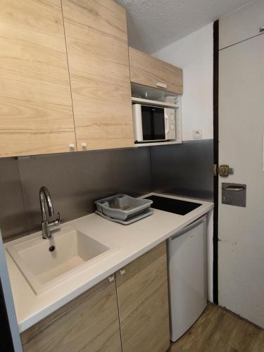 une cuisine avec un évier et un micro-ondes dans l'établissement Résidence Etoile - Studio pour 2 Personnes 284, à La Plagne Tarentaise