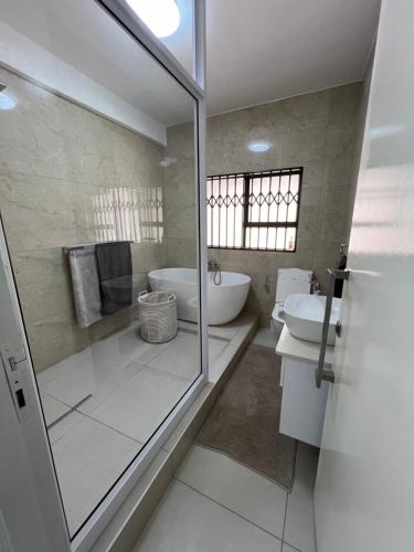 a bathroom with a shower and a tub and a sink at Shobalenku Opulent apartments in Mbabane