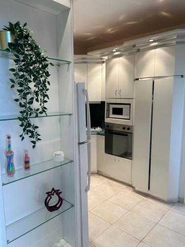 a white kitchen with a refrigerator and some shelves at Natanya Sea View in Netanya