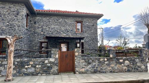 a stone house with a stone wall and a wooden door at Black Rock Agria in Agria
