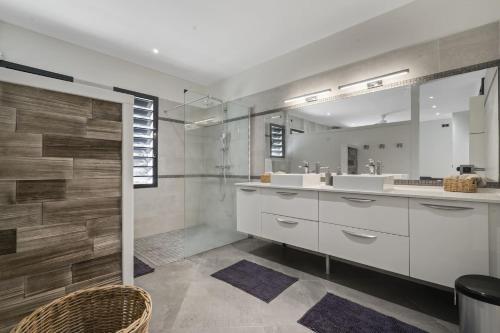 a bathroom with two sinks and a shower with a mirror at Villa Kimloa in Case-Pilote