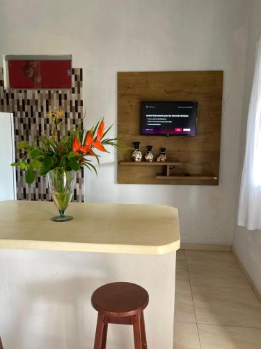 a kitchen with a vase of flowers and a tv on the wall at Residencial Lima in Trancoso