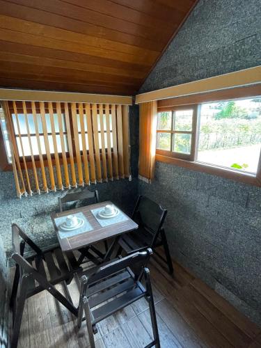 a table and chairs in a room with two windows at Pousada Ilha da Magia in Florianópolis