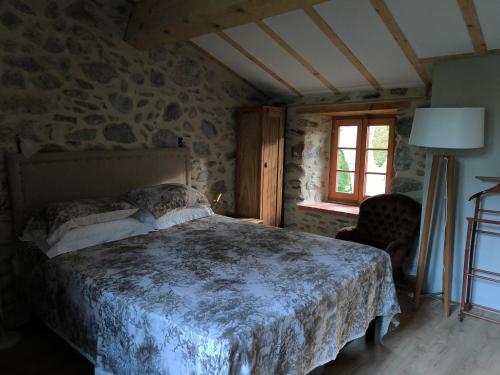 a bedroom with a bed with a stone wall at Gite du grand cèdre in CampÃ´me