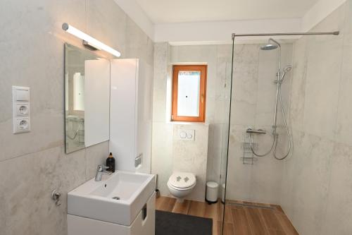 une salle de bain blanche avec lavabo et douche dans l'établissement Búzavirág Ház, à Siófok
