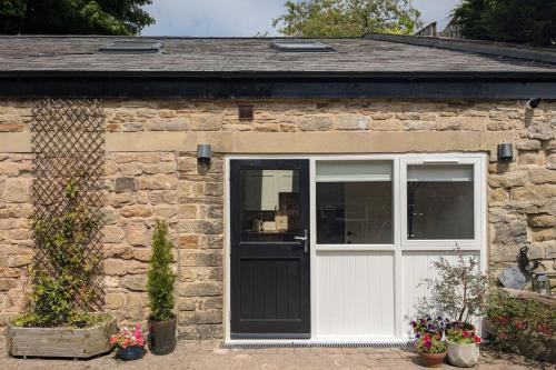 a stone house with a white door and a window at Light, modern detached studio in Eyam in Eyam