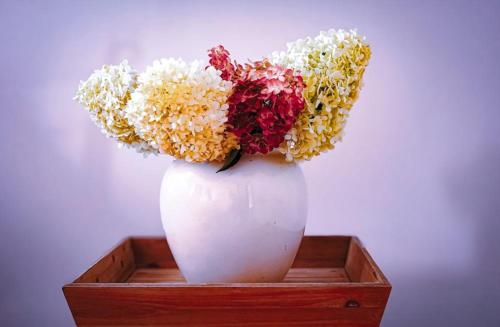 a white vase with flowers in a wooden box at Willa pod Lipami in Bartoszyce