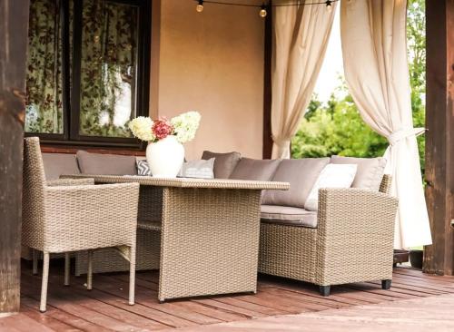 a wicker table and chairs on a patio with a couch at Willa pod Lipami in Bartoszyce