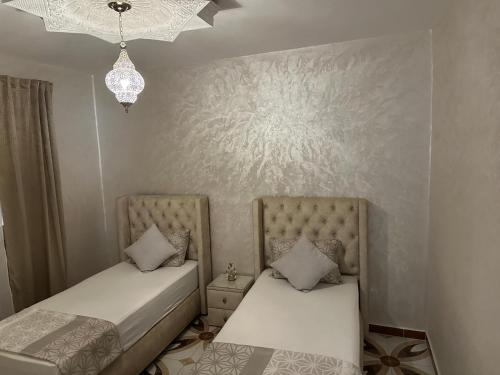 a bedroom with two beds and a chandelier at S&R Appartements in M'diq
