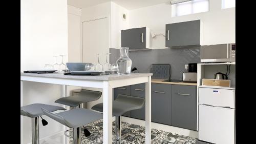 une cuisine avec une table blanche et quatre chaises dans l'établissement La Petite Cour, à Chartres