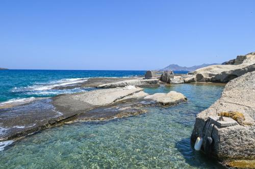 a pool of water with rocks and the ocean at Fisherman's Syrma House in Pachaina