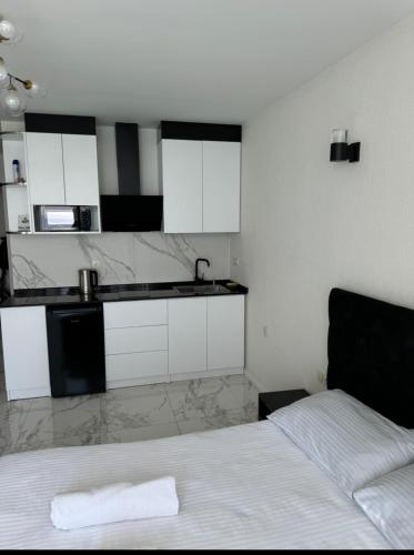 a bedroom with a bed and a kitchen with white cabinets at SEA in Batumi