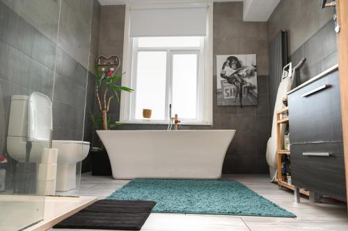 a bathroom with a white tub and a green rug at Audenshaw Spacious Double Room in Manchester