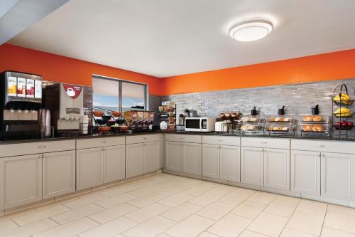 a coffee shop with orange walls and white cabinets at Howard Johnson by Wyndham Harrisonburg in Harrisonburg
