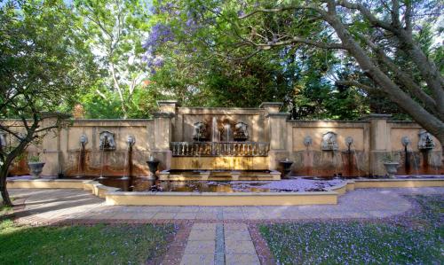 a fountain in the middle of a park with trees at Franschhoek Country House & Villas in Franschhoek